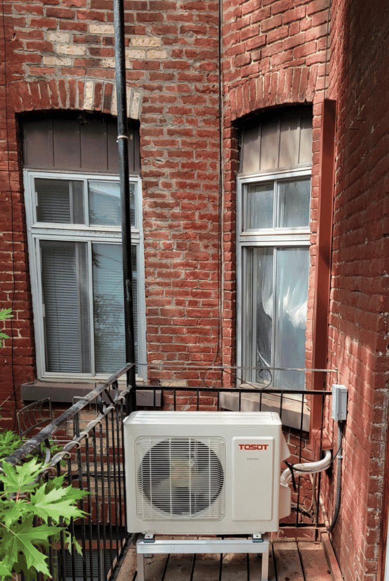 Thermopompe murale Tosot installée par AirGreen sur un balcon de brique