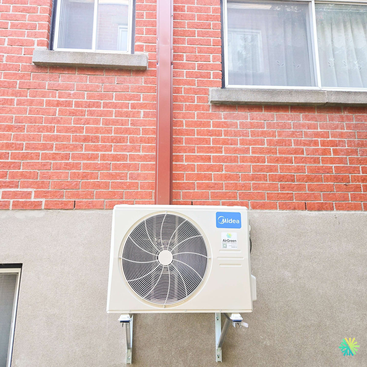 Installation d’une thermopompe murale MIDEA MIDEA35 à Saint-Jean-Baptiste : unité extérieure sur supports muraux et conduit discret sur façade de brique