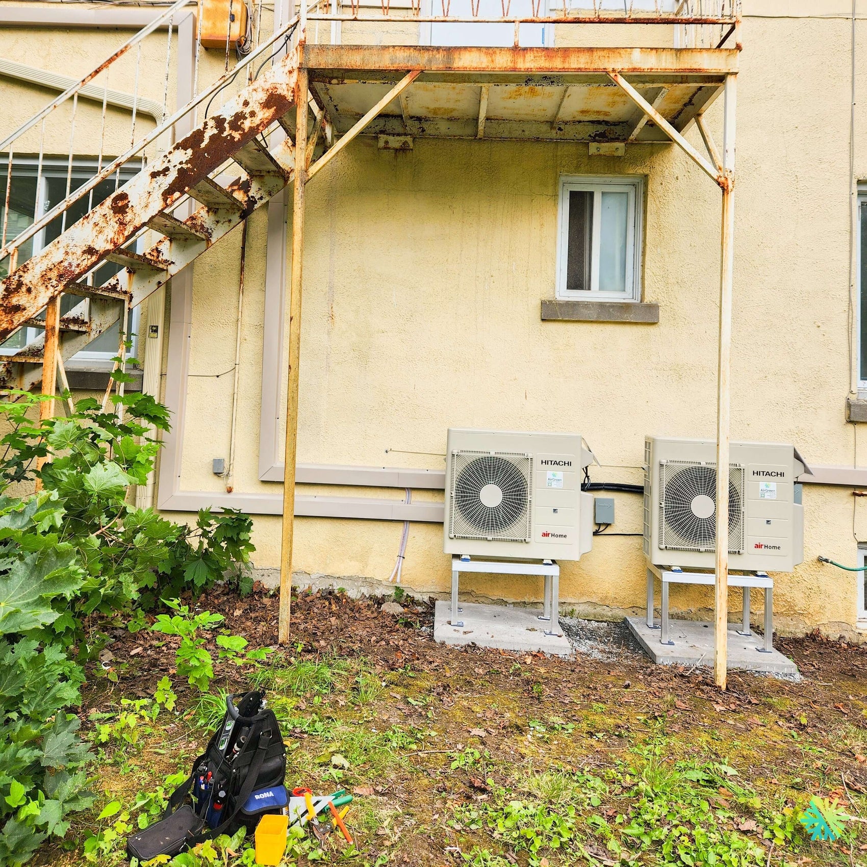 Installation de deux thermopompes murales Hitachi airHome 800 à Auteuil, Laval, sous un escalier extérieur métallique