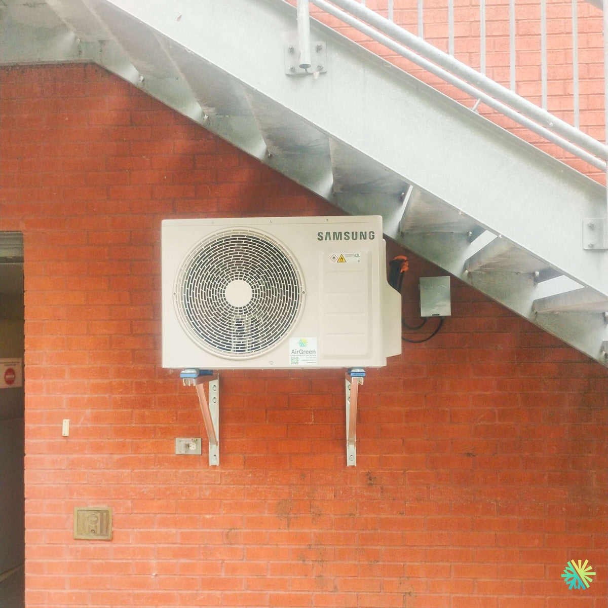 Installation d’une thermopompe murale Samsung WindFree™ MaxHeat sous un escalier extérieur à Boisbriand, sur la Rive Nord