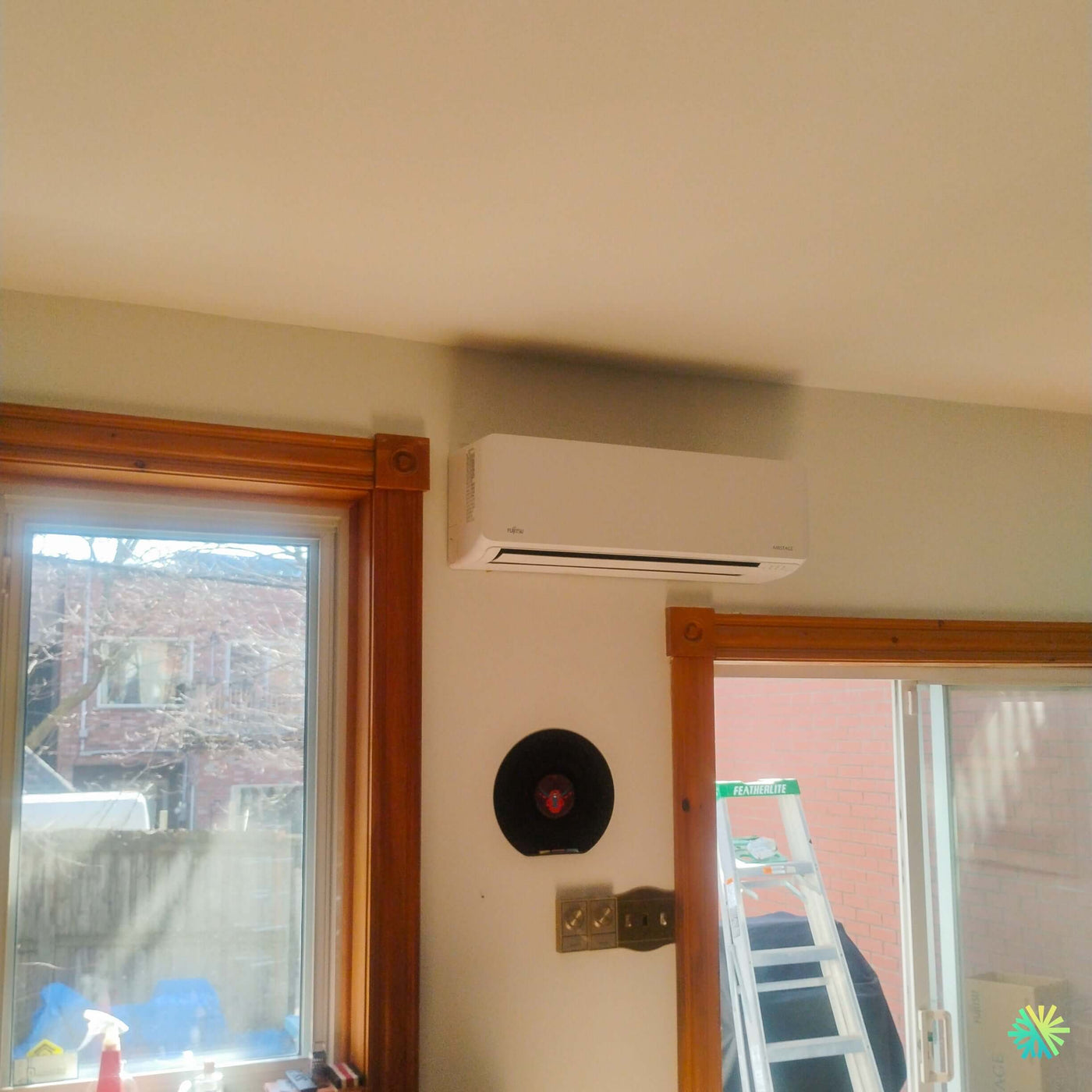 Installation d’une thermopompe murale FUJITSU ALTAIR 700 Mini Split à LaSalle, Montréal : une intégration soignée au-dessus d’une baie vitrée dans une maison à cachet classique