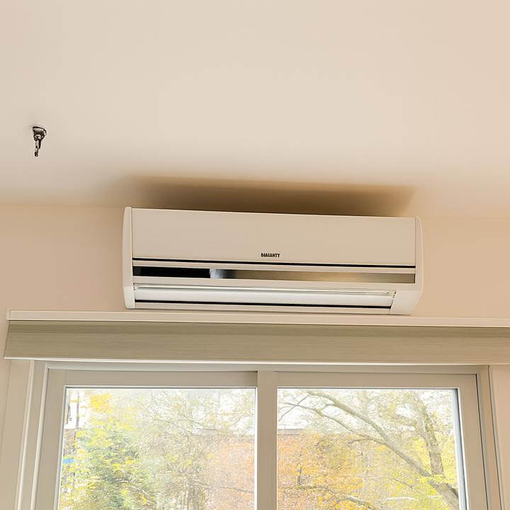 Homme frustré assis sous une thermopompe murale inefficace, guide: Comment dépanner une thermopompe murale qui ne chauffe pas correctement?