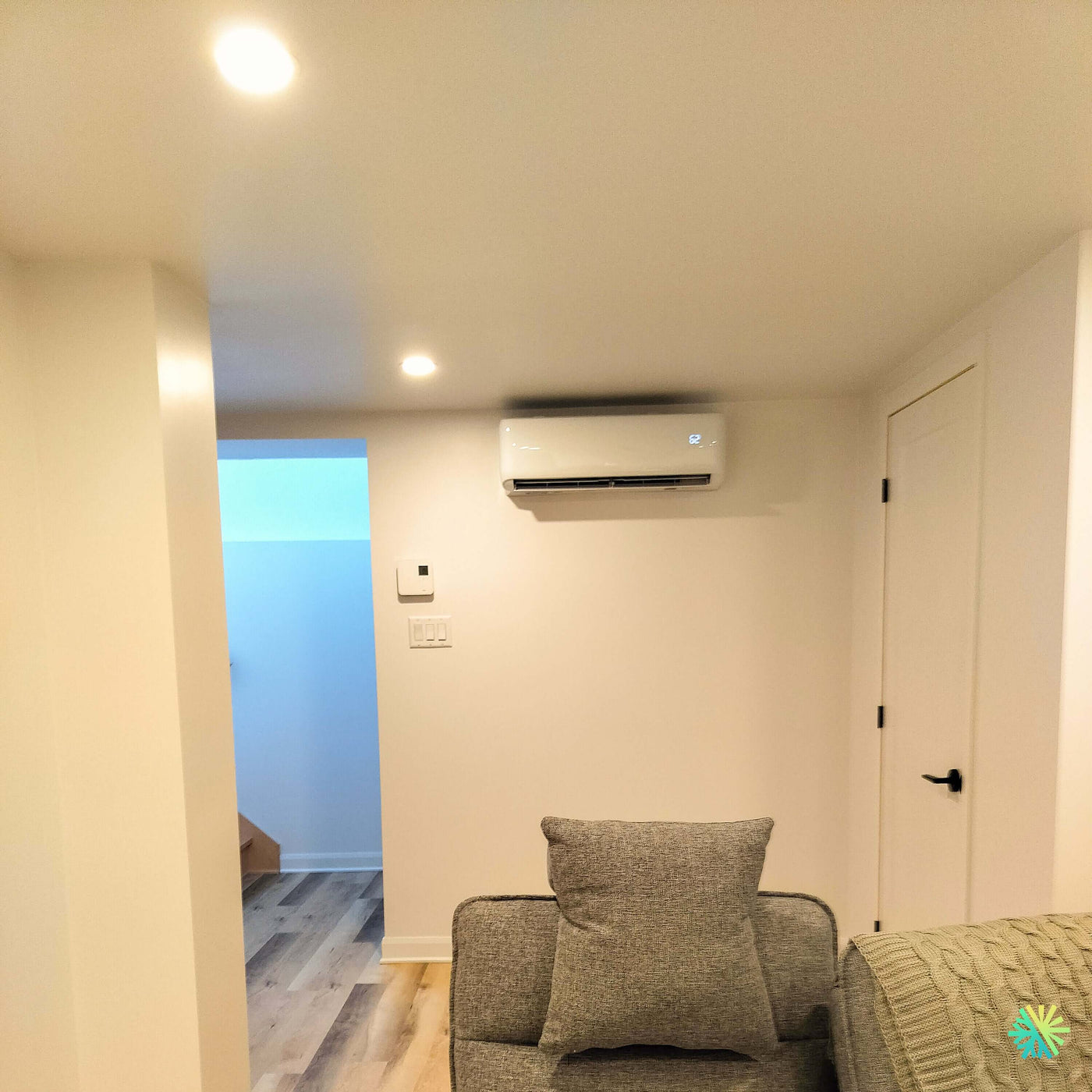 Installation d’une thermopompe GREE FREE MATCH R32 DoubleZone 2-Zones 2-Têtes à Saint-Laurent dans un espace résidentiel rénové avec intégration murale au-dessus d’un salon