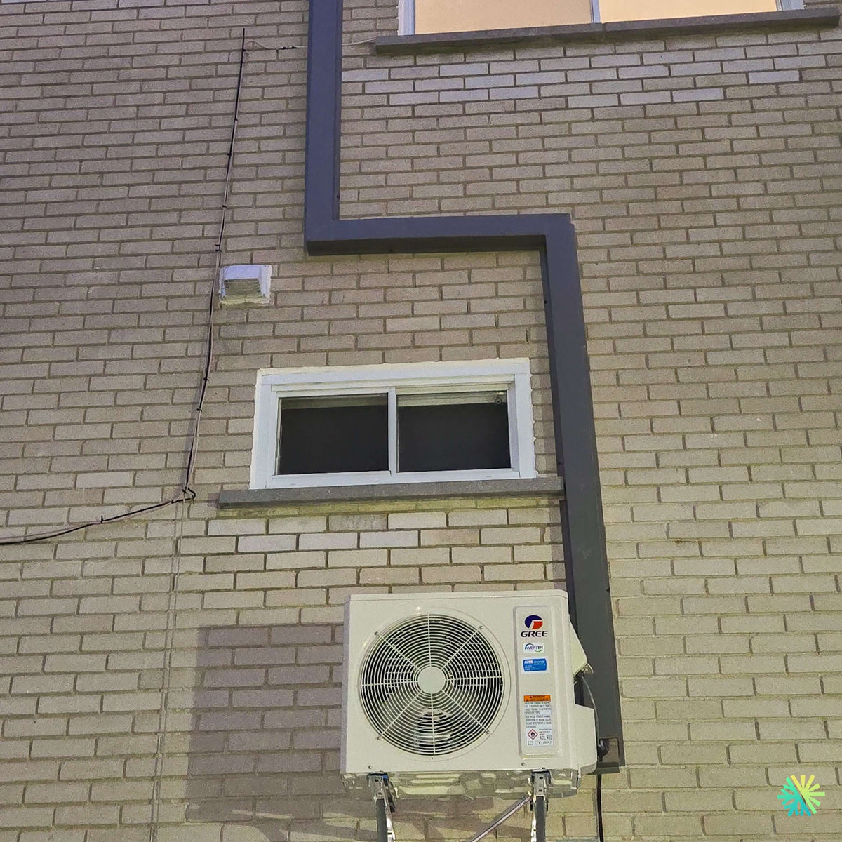 Installation d’une thermopompe DoubleZone GREE FREE MATCH R32 à Delson : système 2 zones avec deux têtes murales et unité extérieure murale sur façade de brique