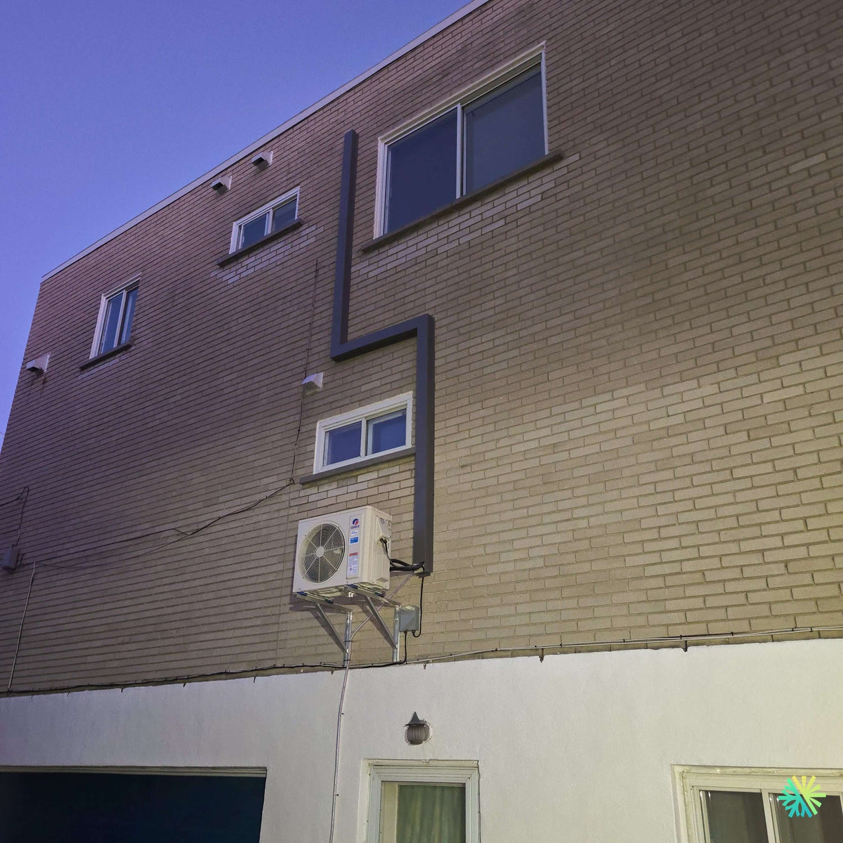 Installation d’une thermopompe murale GREE CROSSOVER R32 à Sainte-Dorothée, Laval : climatiseur mini split avec parcours extérieur sur façade de brique