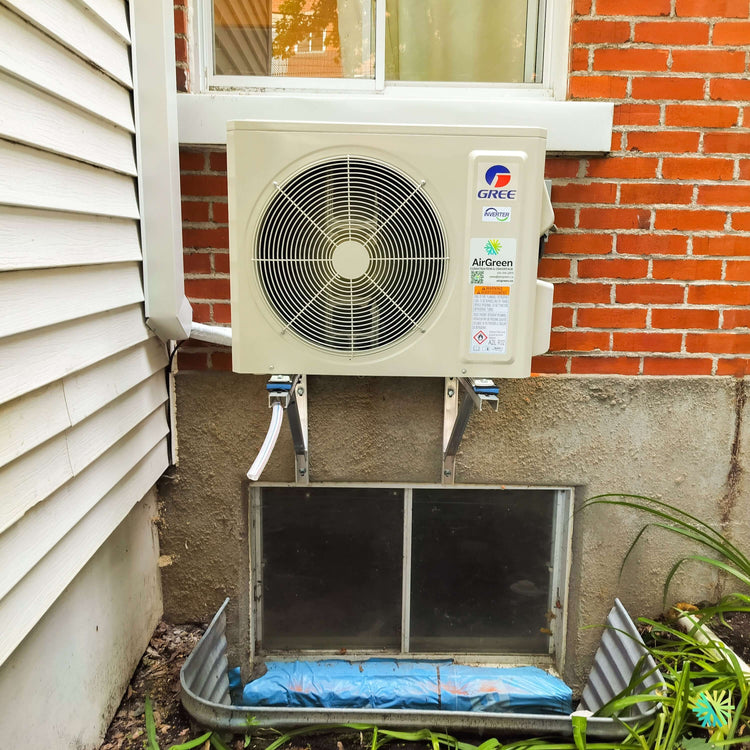 Installation d’une GREE VITA R32 Thermopompe Murale - Climatiseur - Mini Split à Saint-Laurent, Montréal, avec unité extérieure sur support mural au-dessus d’une margelle de sous-sol