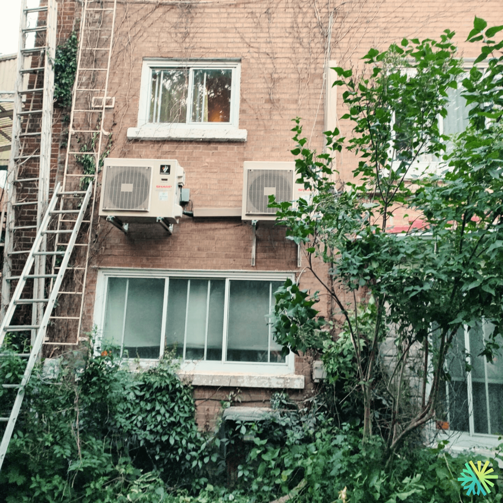 Installation de deux thermopompes murales Sharp ZU1 sur un immeuble en brique au Plateau-Mont-Royal