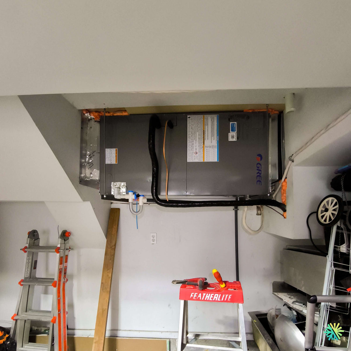 Installation d'une thermopompe centrale GREE FLEXX R32 suspendue dans un plafond de garage à Saint-Sébastien, dans le Haut-Richelieu