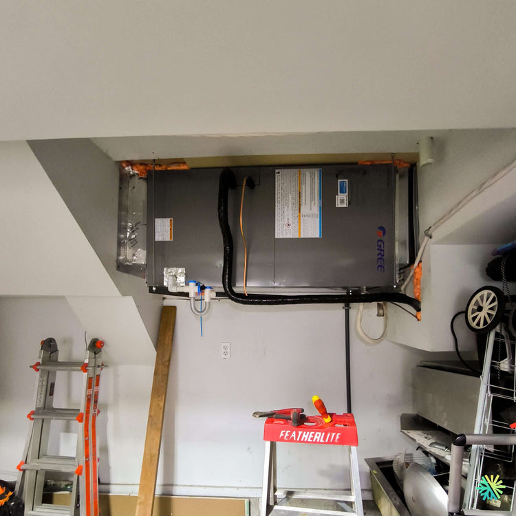 Installation d'une thermopompe centrale GREE FLEXX R32 suspendue dans un plafond de garage à Saint-Sébastien, dans le Haut-Richelieu