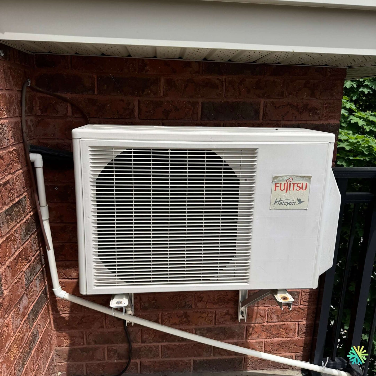 Fujitsu air conditioning unit mounted on red brick wall outdoors, providing energy-efficient cooling.
