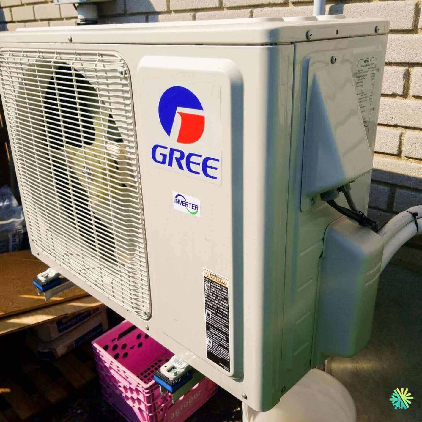 Gree inverter air conditioning unit mounted outdoors against a brick wall.