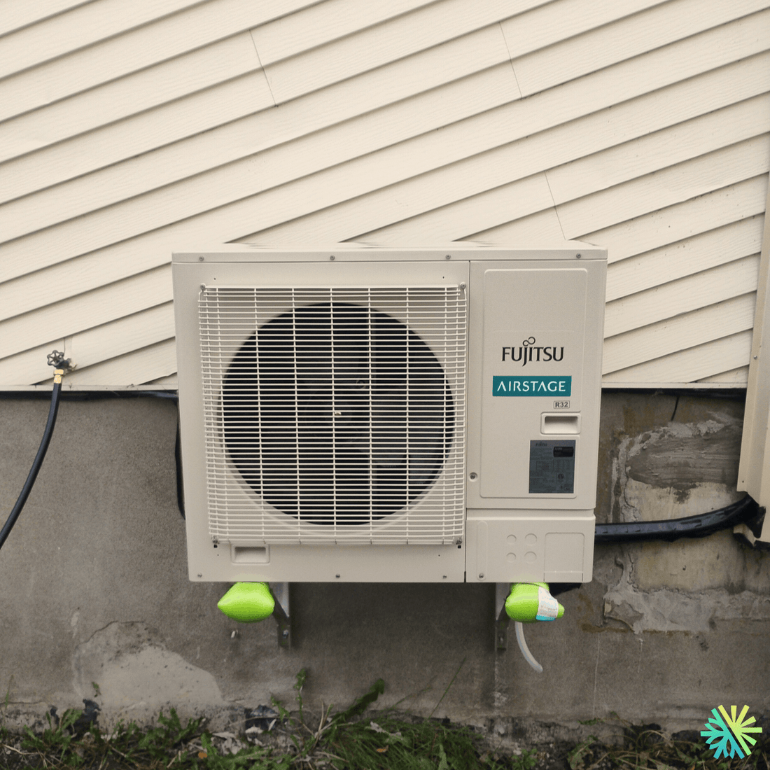 Outdoor Fujitsu air conditioner unit attached to the side of a house, showcasing energy-efficient climate control technology.