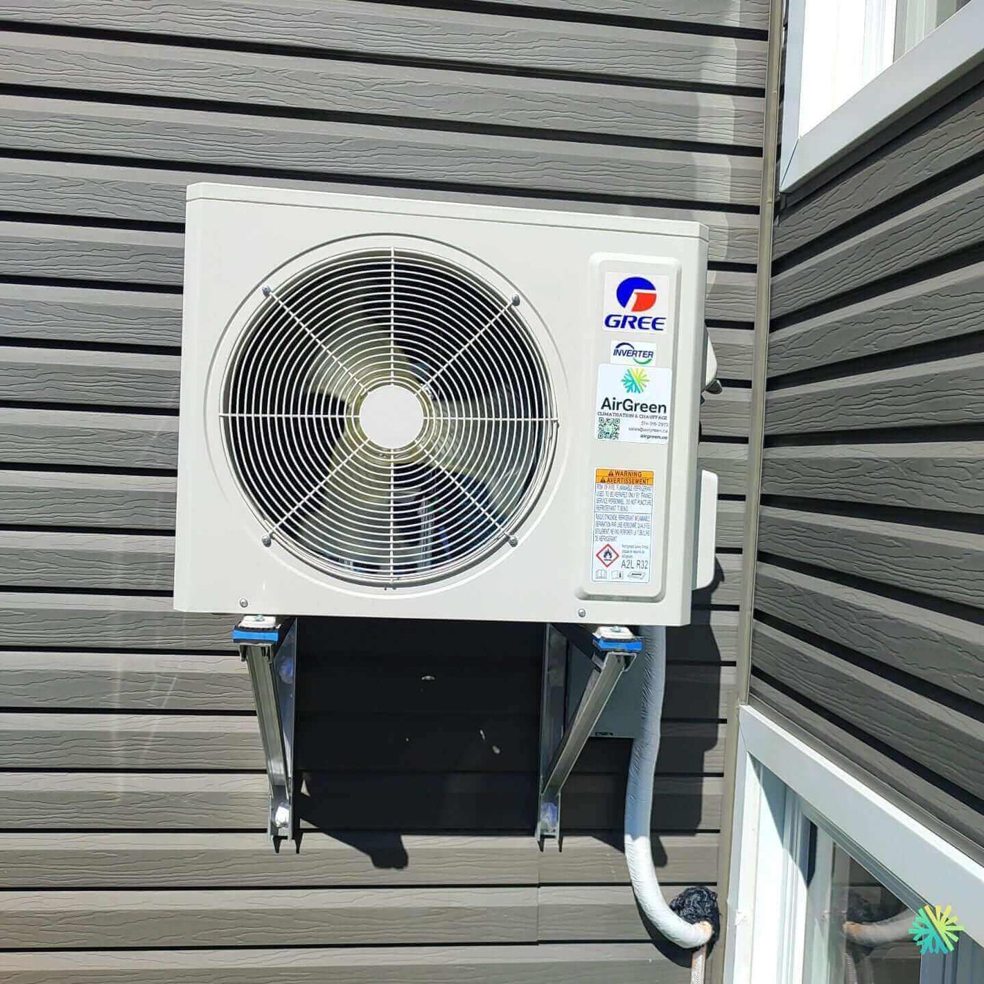 Outdoor Gree air conditioning unit mounted on a wall of a house.