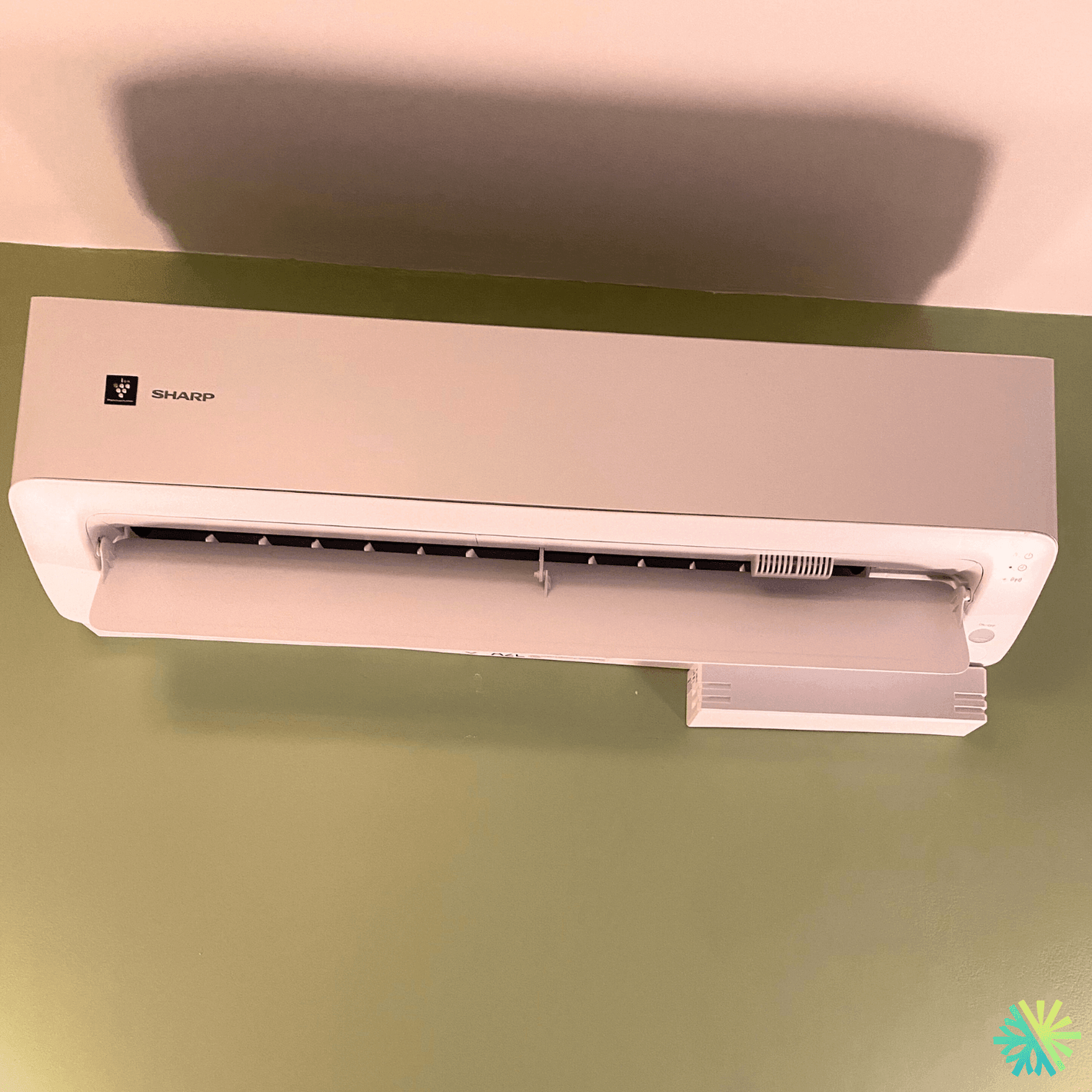 Sharp air conditioner mounted on a green wall, modern home cooling solution