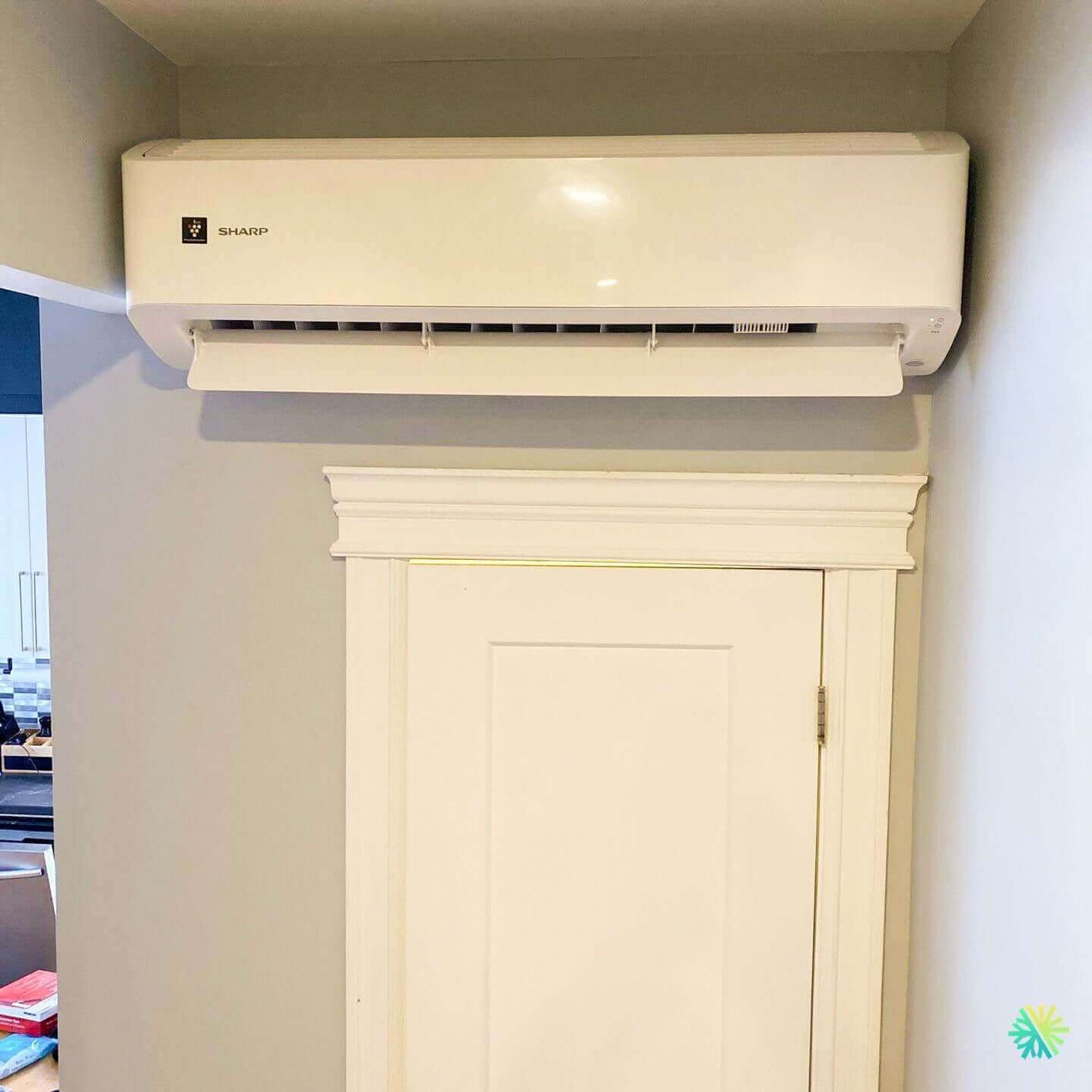 Wall-mounted Sharp air conditioner above a door in a home interior for efficient cooling.
