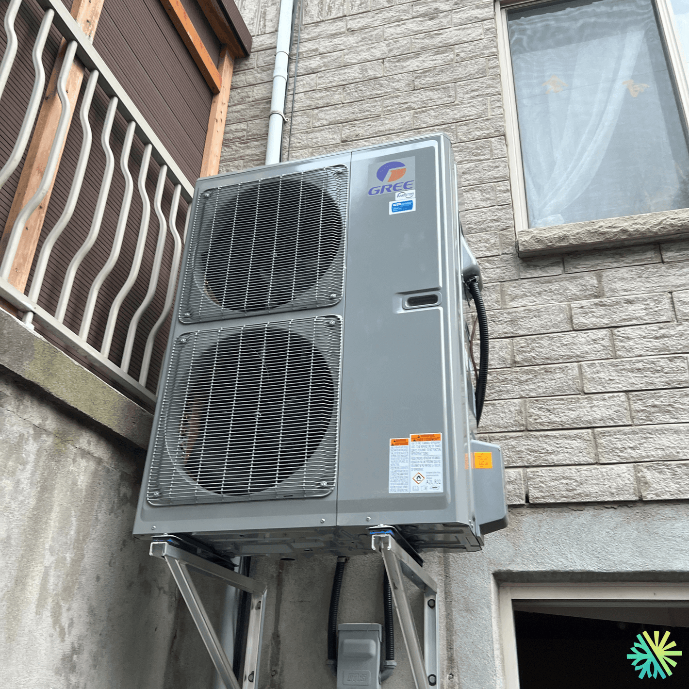 Outdoor Gree heat pump installed on a concrete wall with a stone building background.