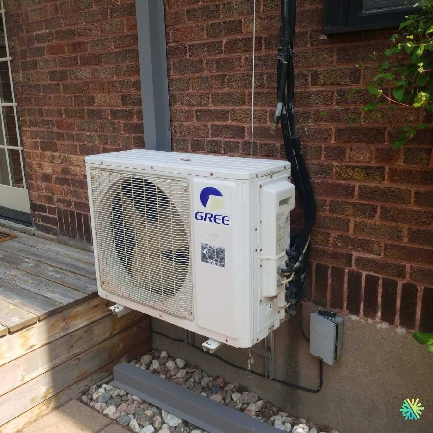 Outdoor Gree air conditioning unit mounted on brick wall, part of residential cooling system.