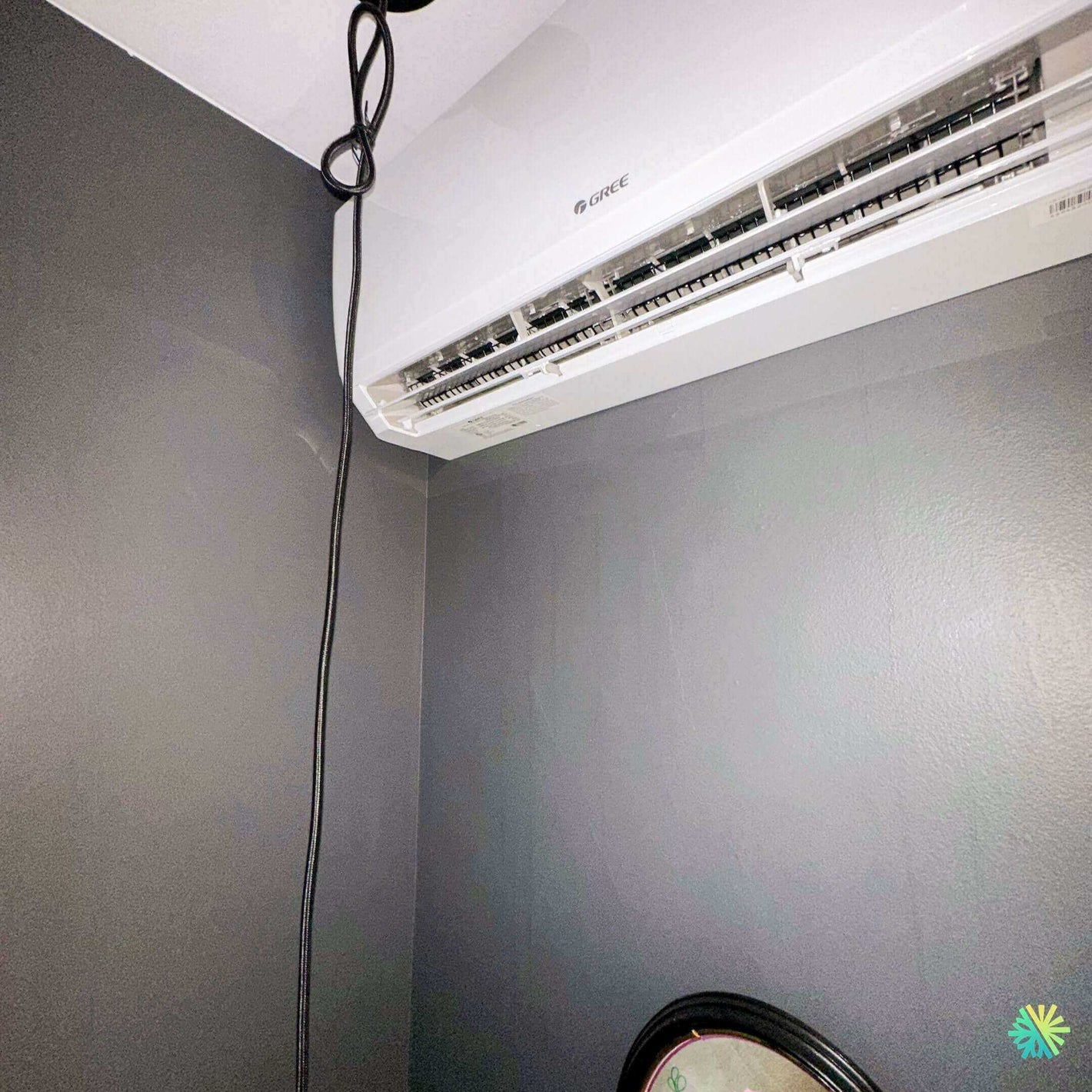 Modern GREE air conditioner installed in a corner of a light grey room, showcasing efficient cooling design.