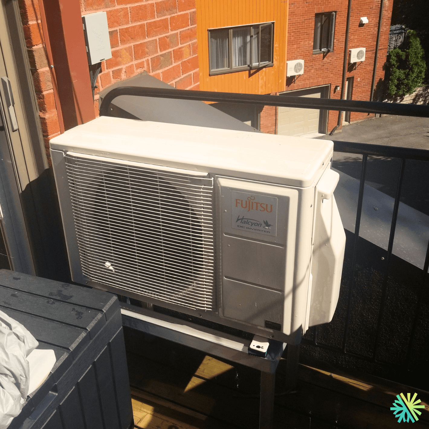 Outdoor Fujitsu Halcyon air conditioning unit installed on a residential balcony against a brick wall.