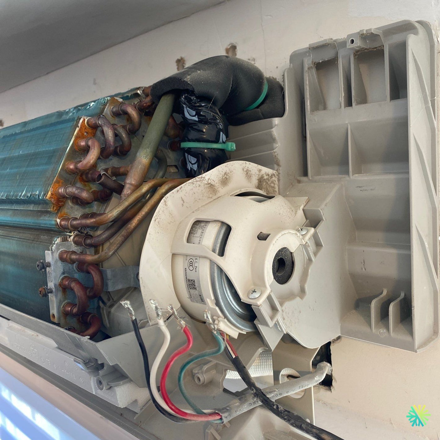 Close-up of indoor air conditioning unit's evaporator coil and fan motor in need of maintenance or repair.