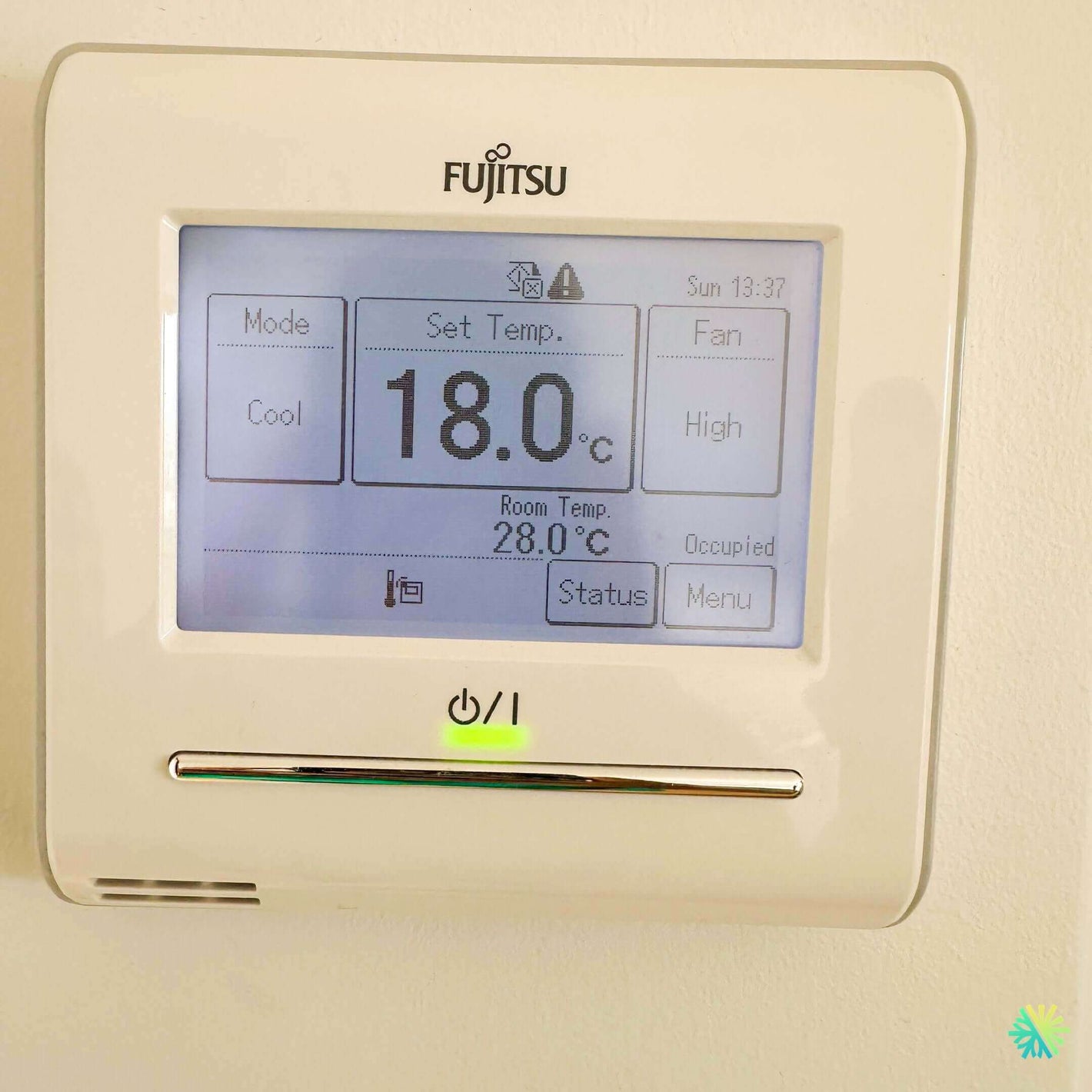 Fujitsu wall-mounted electronic thermostat showing a set temperature of 18 degrees Celsius with room temp at 28 degrees.