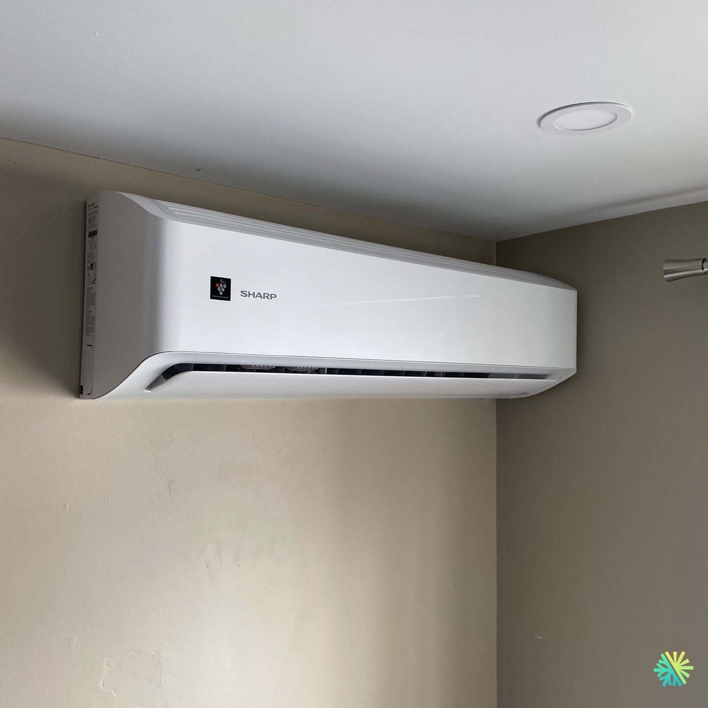 Wall-mounted air conditioner unit installed in a room corner, showing sleek and modern design with energy-efficient performance.