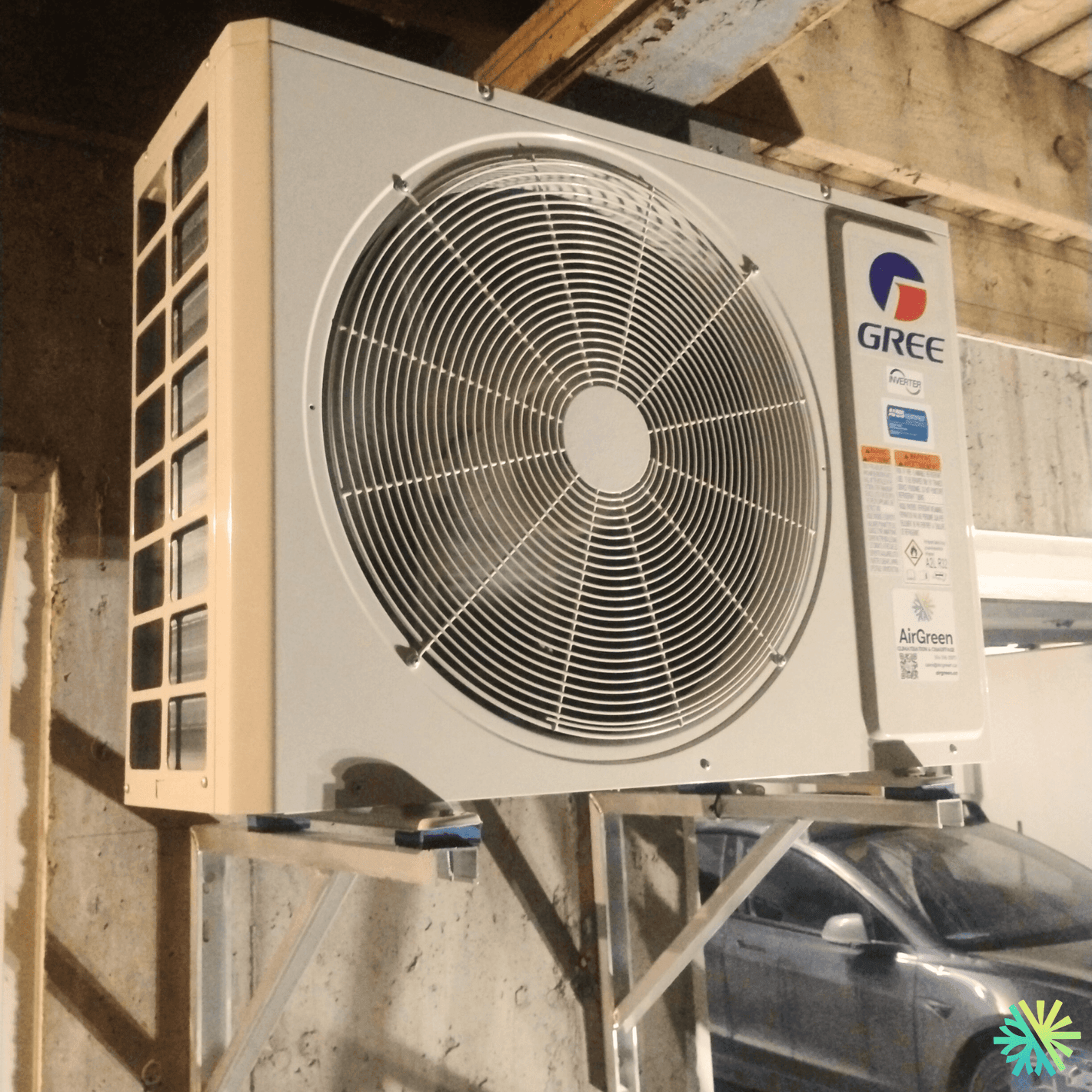 Mounted GREE air conditioning unit with fan in a garage setting.