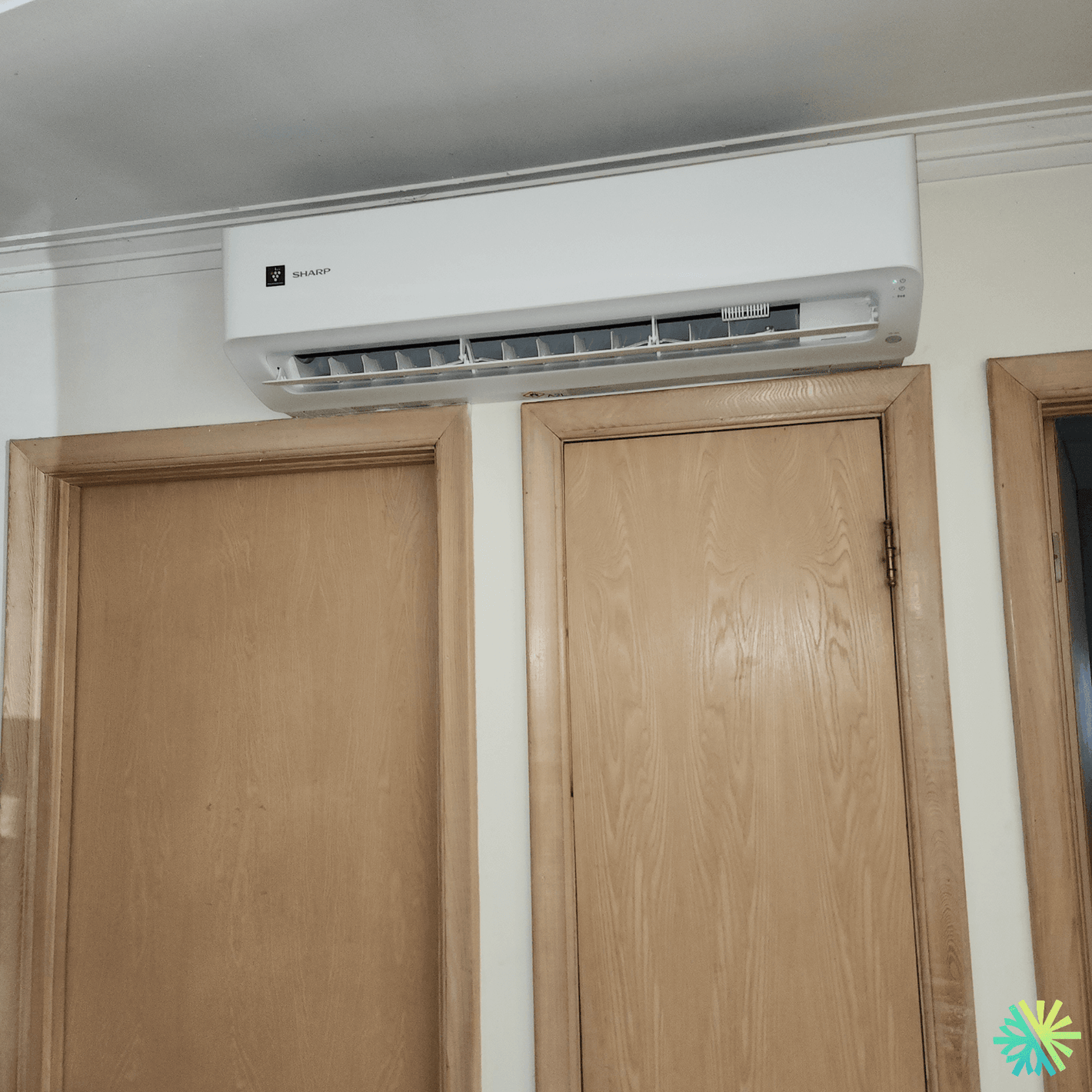 Sharp air conditioner mounted above wooden doors in an interior setting
