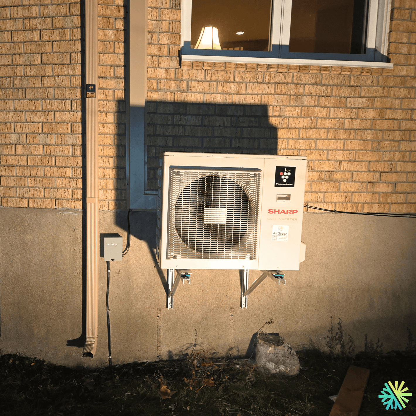 Wall-mounted air conditioning unit outside a brick house illuminated at night