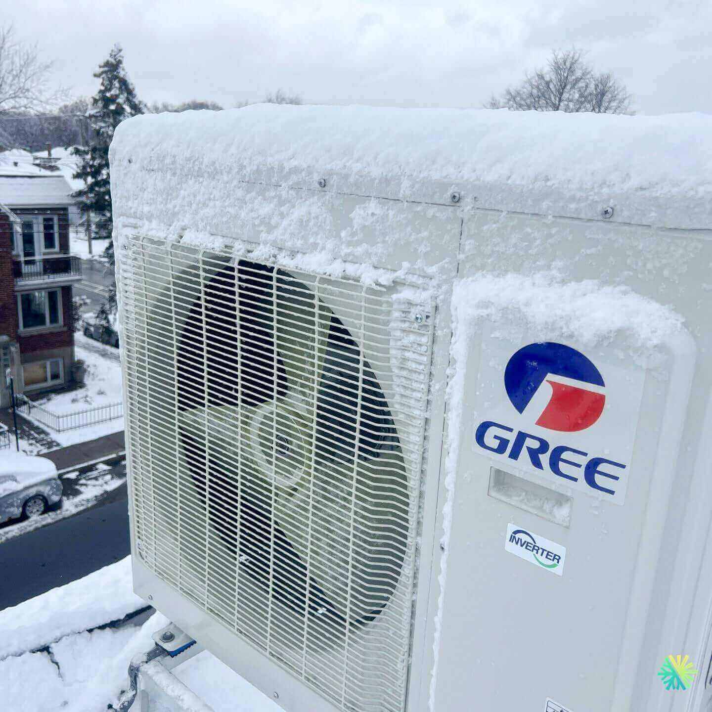 Outdoor Gree HVAC unit covered in snow on a residential rooftop, showcasing energy efficiency in winter conditions.