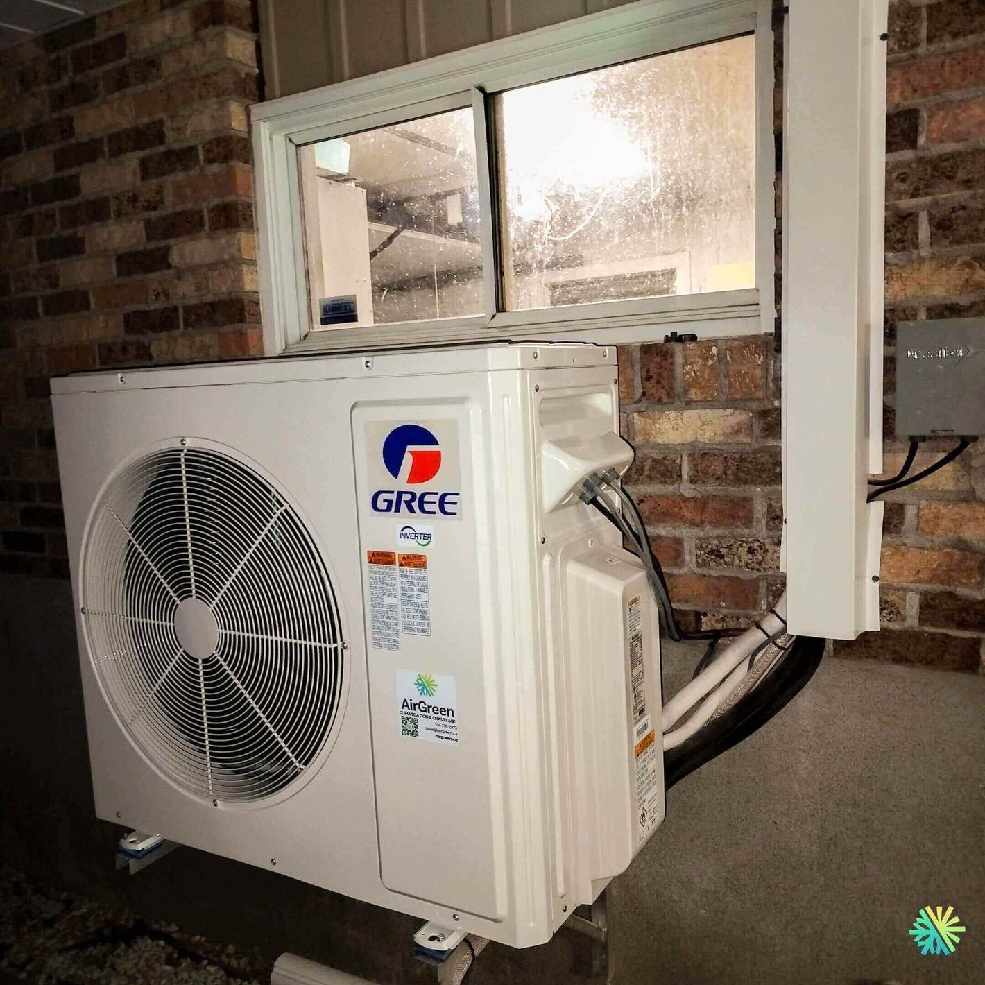Gree air conditioning unit installed on a brick wall outside a window.
