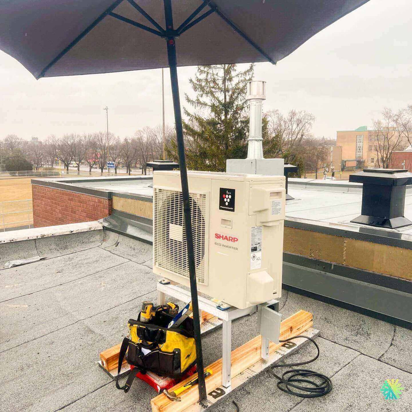 Rooftop air conditioning unit with tools under an umbrella on a cloudy day