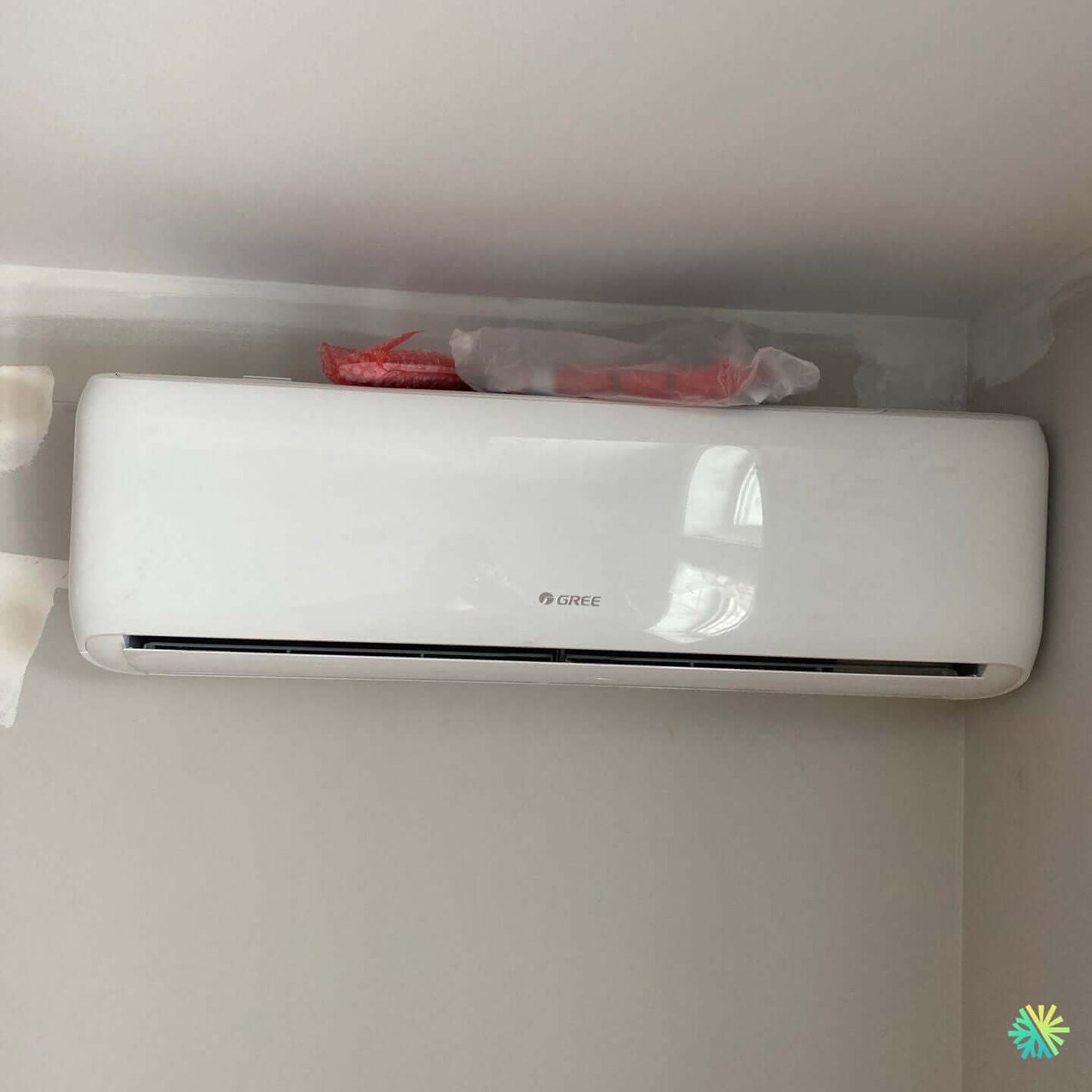 Wall-mounted white air conditioner unit installed in a corner of a room