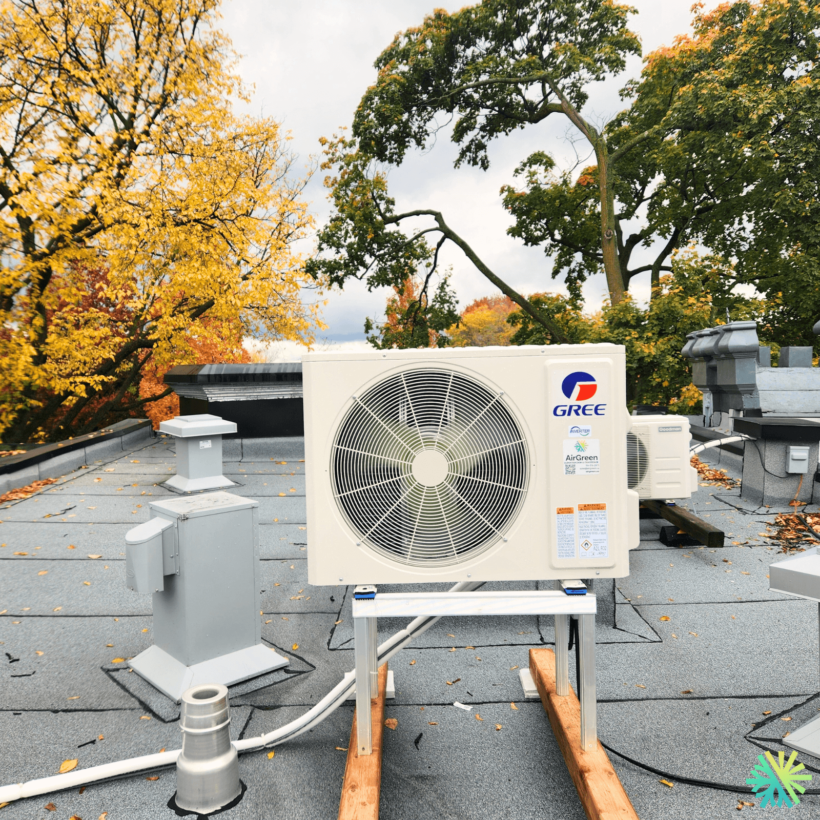 Outdoor air conditioning unit on a rooftop with autumn trees in the background.