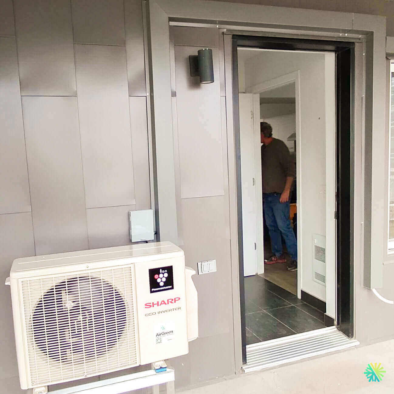 Outdoor air conditioning unit near modern building entrance with open door