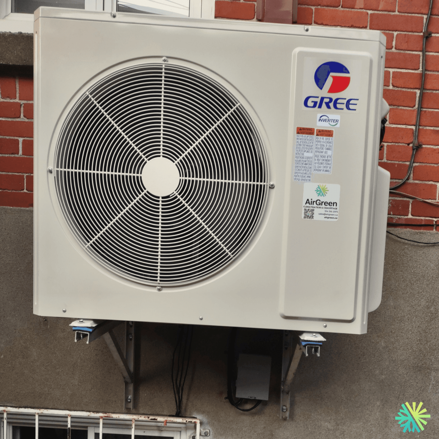 Wall-mounted Gree air conditioning unit with fan and logo on a brick wall, showcasing energy-efficient cooling technology.