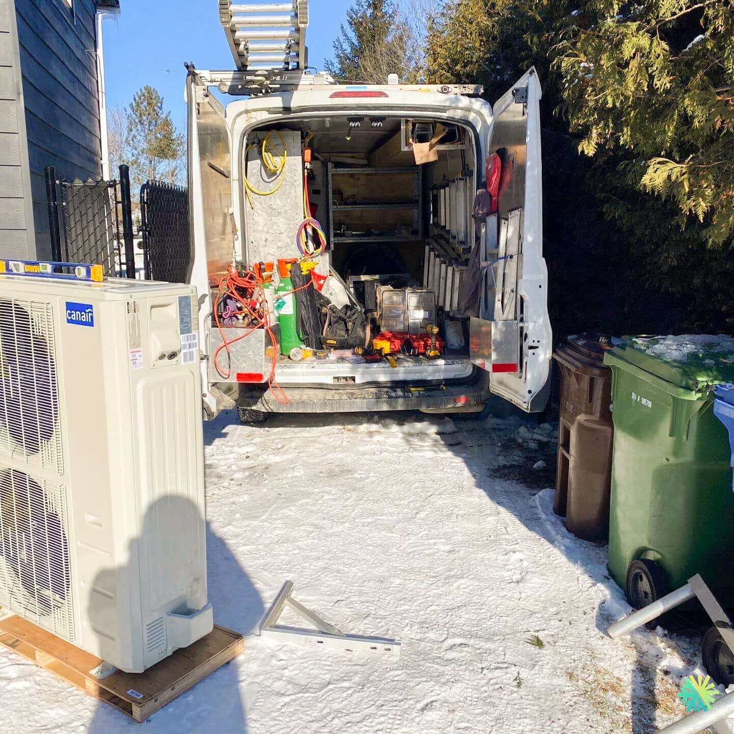 HVAC technician van with tools and equipment ready for air conditioning installation on a snowy driveway.