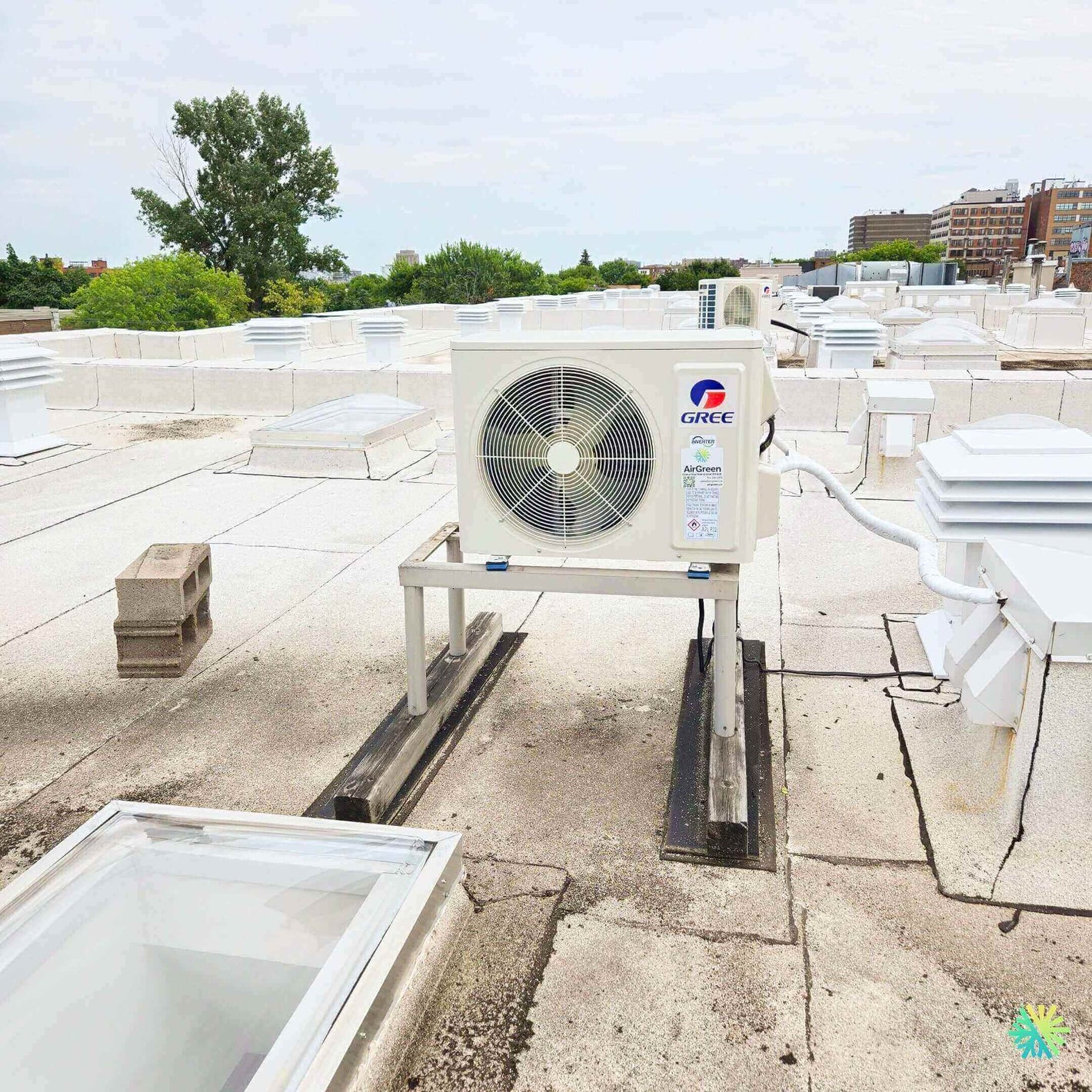 Rooftop Gree air conditioning unit on a commercial building with urban landscape in the background.