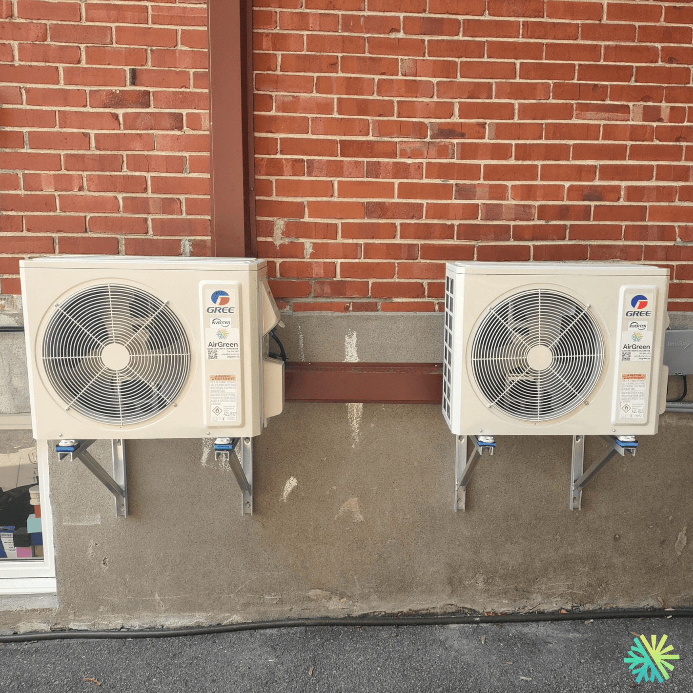 Two Gree air conditioning units mounted on a brick wall outside, showcasing energy-efficient cooling solutions.