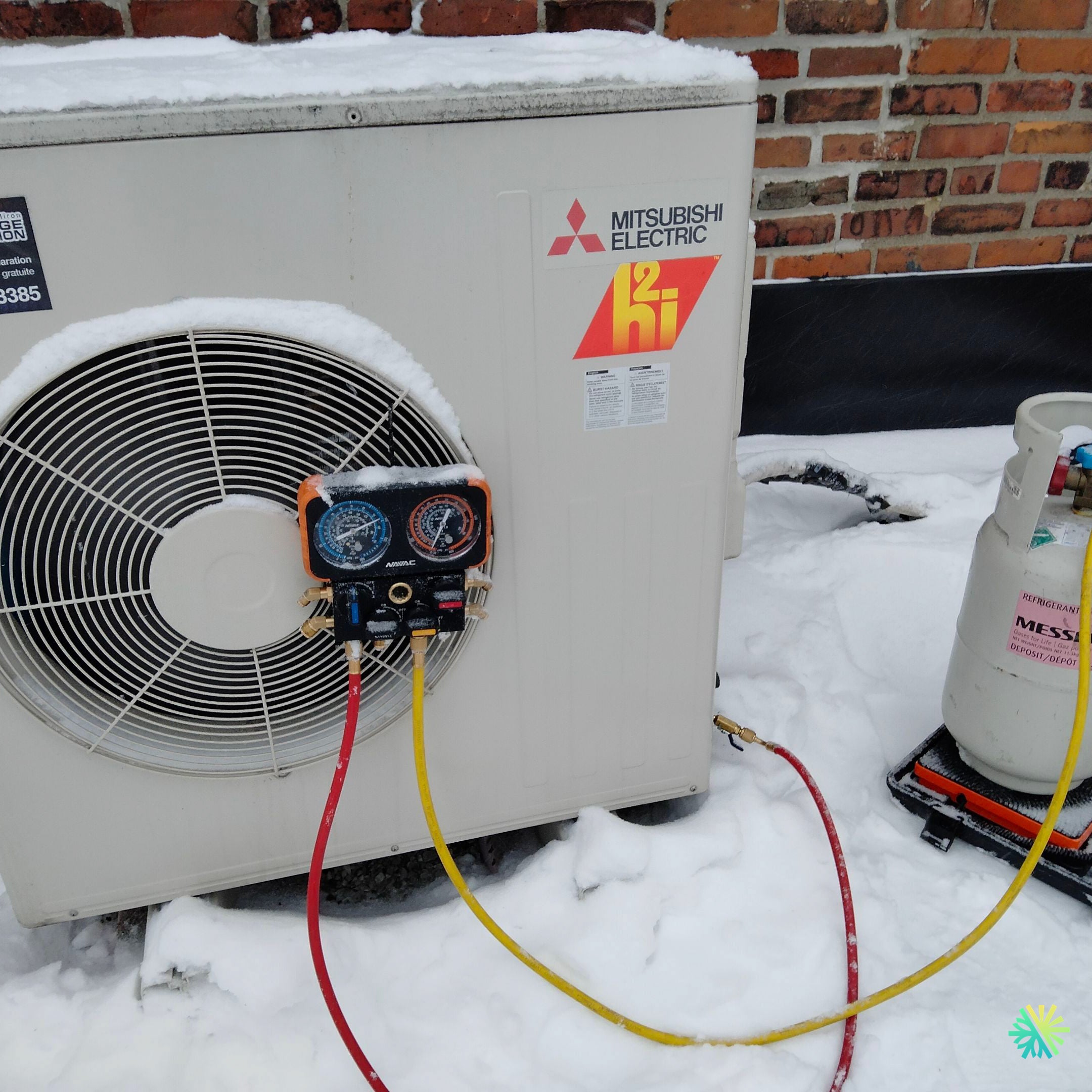 Outdoor Mitsubishi Electric HVAC unit with maintenance tools and snow, showcasing winter repair and servicing of heating systems.
