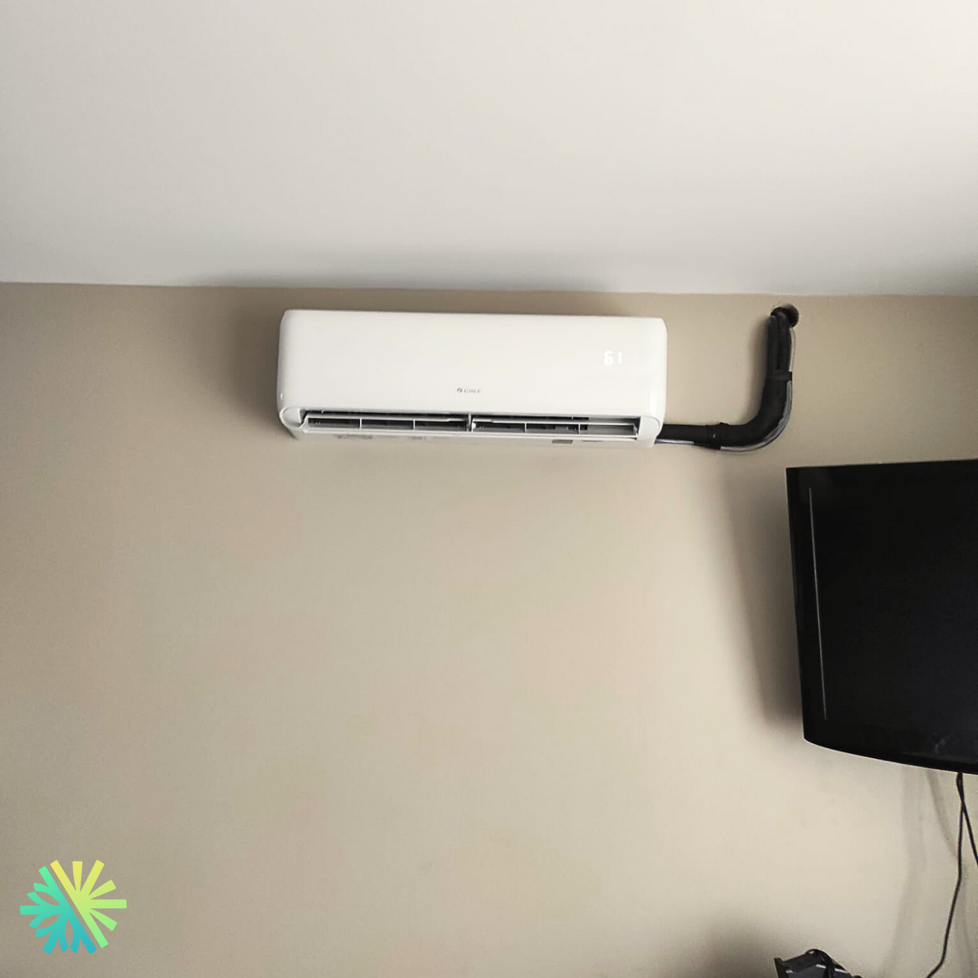 Wall-mounted air conditioner unit above a television, highlighting modern home cooling solutions.