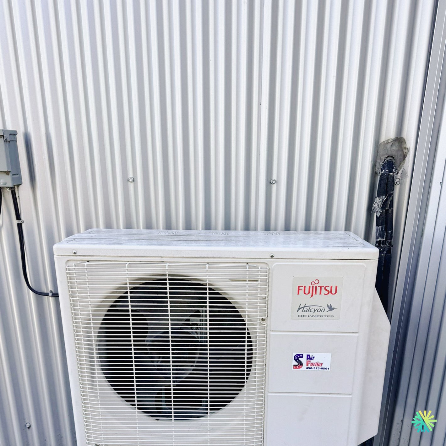 Fujitsu Halcyon outdoor air conditioning unit mounted on a corrugated metal wall.