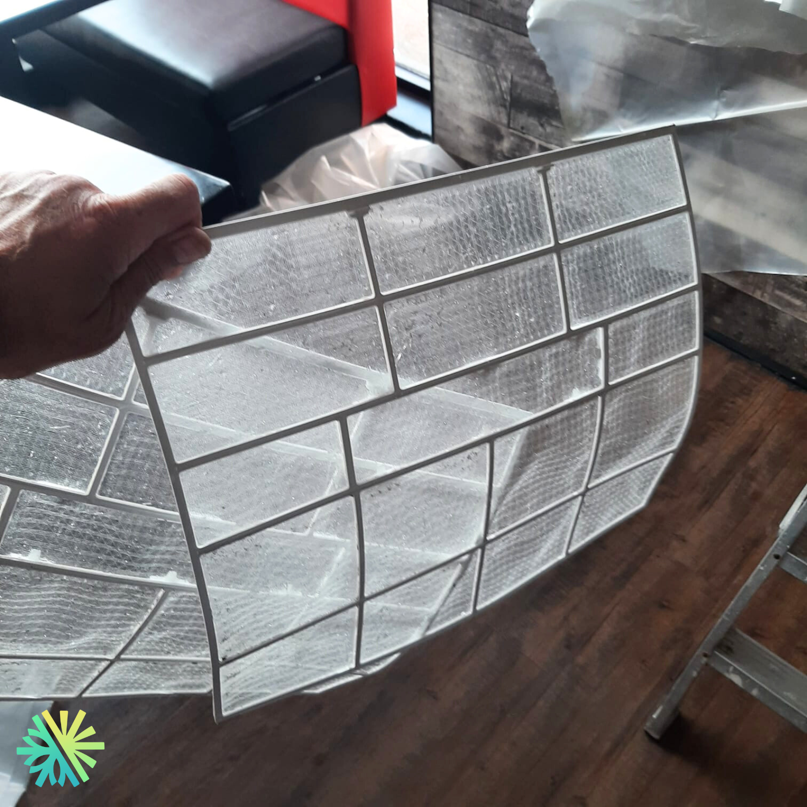 Hand holding a clean air conditioner filter indoors, showcasing dust-free mesh and home maintenance.
