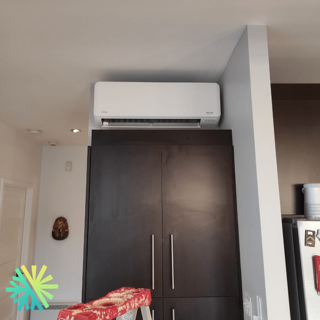 Wall-mounted air conditioner above dark wood cabinet in a modern room with white walls and ceiling.
