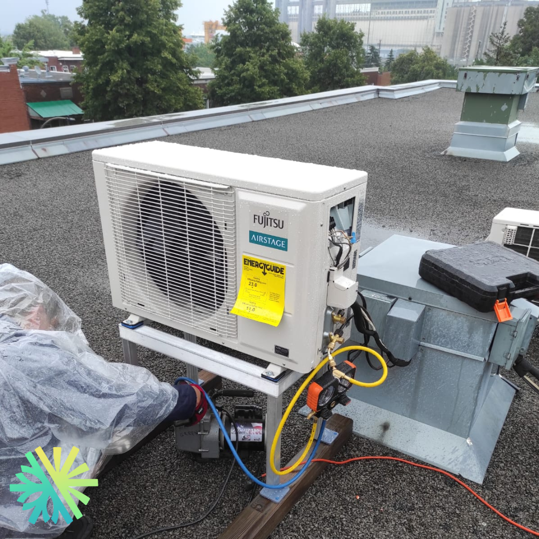 Technician working on a Fujitsu Airstage HVAC unit on a rooftop, showcasing energy efficiency and repair tools during maintenance.
